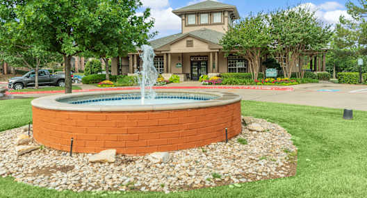 a fountain in the middle of a lawn in front of a house