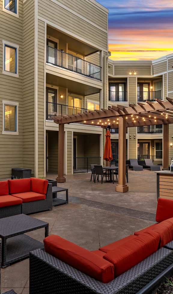 A patio area with red couches and a pergola. at West 39th Street Apartments, Kansas City, 64111