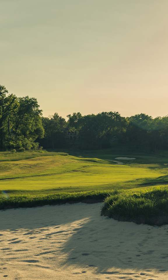 A beautiful golf course with a green fairway and trees in the background.