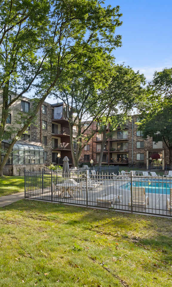 A sunny day at a residential complex with a pool and green lawn.