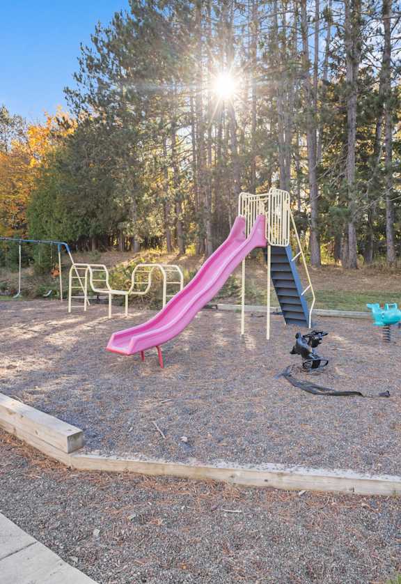 A playground with a pink slide and a wooden swing set.