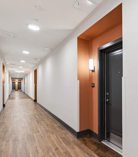 A long hallway with a black door on the right.