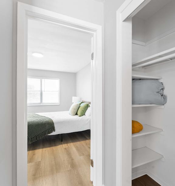 A white bedroom with a bed and a small closet.