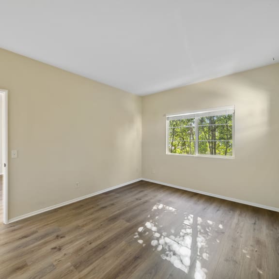 a bedroom with hardwood floors and beige walls at The Village Apartments, Van Nuys California
