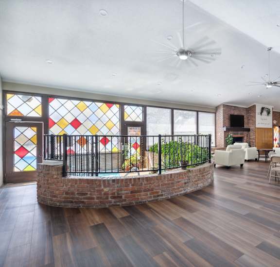 A room with a round table and chairs and a brick wall with a window.