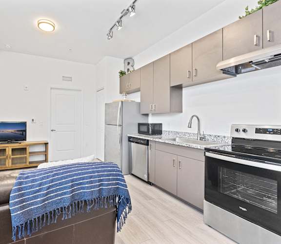 a living room with a leather couch and a kitchen with stainless steel appliances