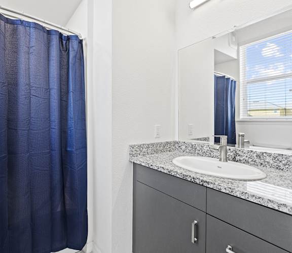 a bathroom with a shower and sink and a blue shower curtain