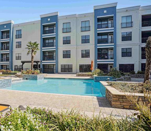 A pool surrounded by a patio and a building.