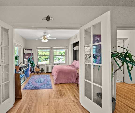A room with a bed, a guitar, and a ceiling fan.