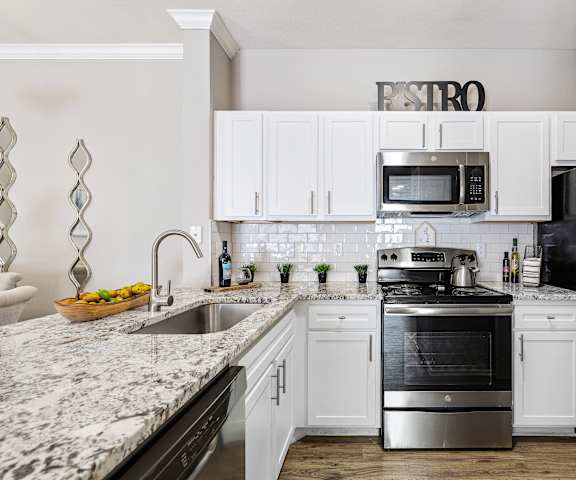 a white kitchen with stainless steel appliances and granite counter tops at Sonterra Apartment Homes, Austin