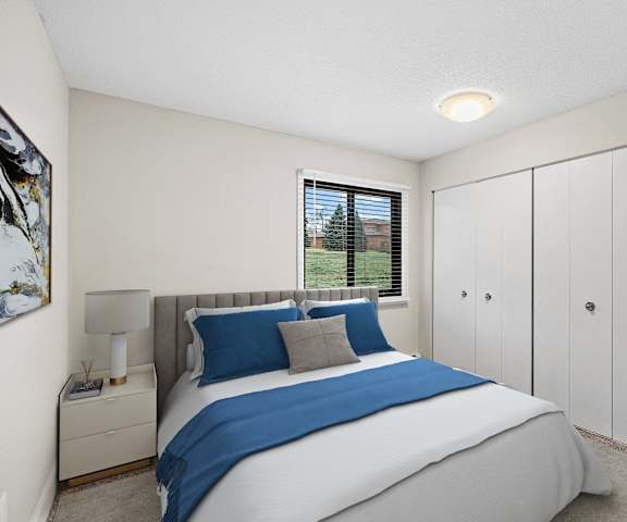A bedroom with a large bed and a window with blinds.
