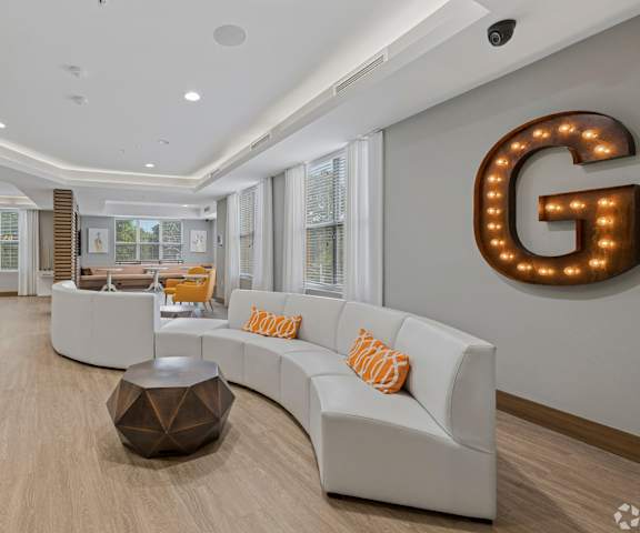 A modern living room with a white sofa and a large letter G on the wall.