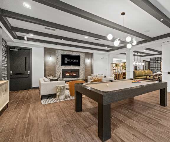 A billiard table is in the middle of a room with a fireplace and a sign that says "Olsworth.".