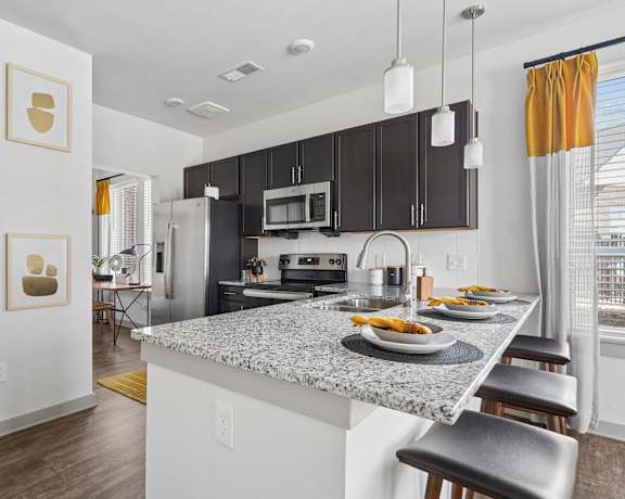 A kitchen with a granite countertop and black cabinets.