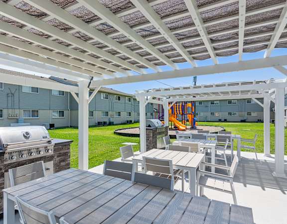 a covered patio with a grill and table and chairs