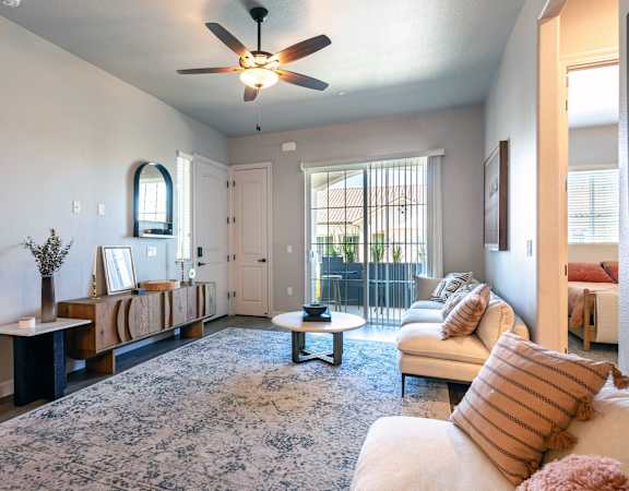 a living room with a ceiling fan and a door to a balcony