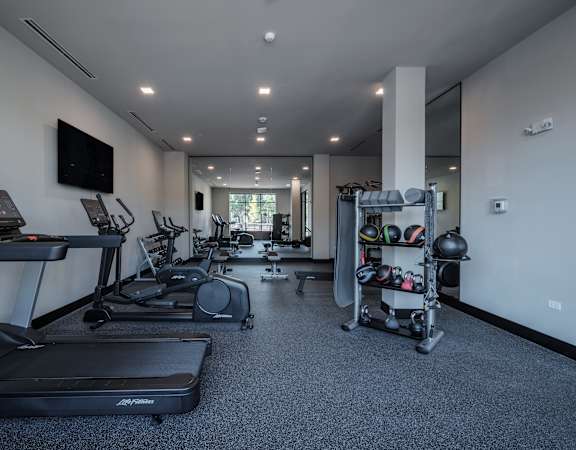 a gym with treadmills and other exercise equipment and a tv