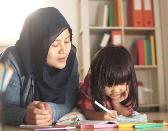 a woman and a child drawing with colored pencils