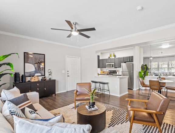 a living room with a couch and chairs and a kitchen
