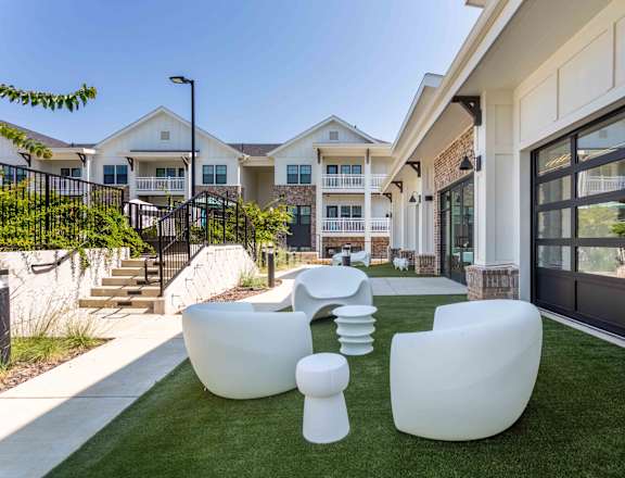 A white outdoor furniture set is placed on a green lawn.