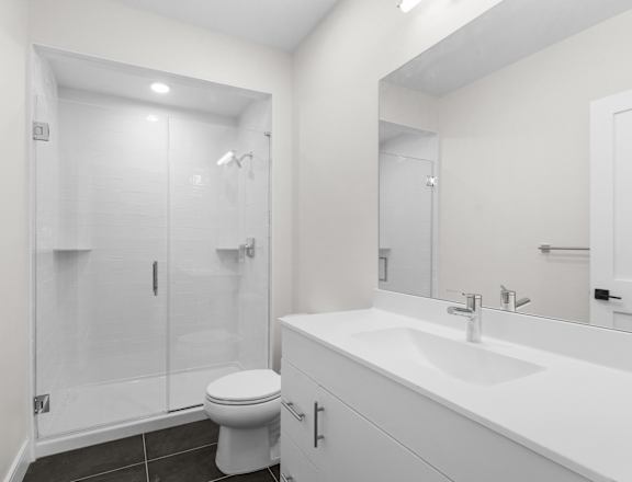 A white bathroom with a toilet, sink, and shower.