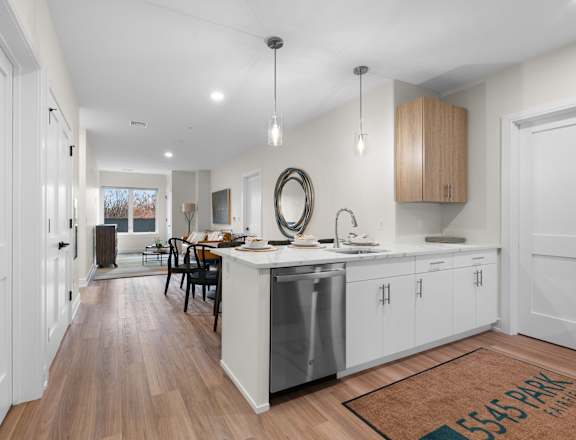 A modern kitchen with white cabinets and a wooden floor.
