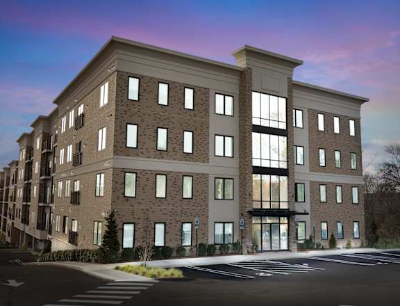 A modern apartment building with a parking lot in front.