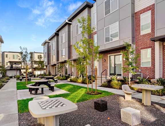 an outdoor courtyard with picnic tables and benches in front of an apartment building