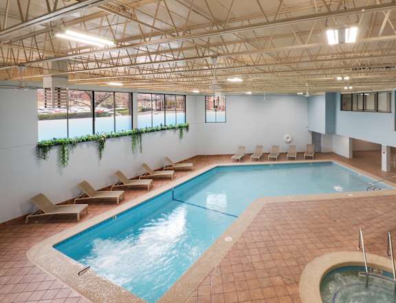 A large indoor swimming pool with a hot tub and lounge chairs.