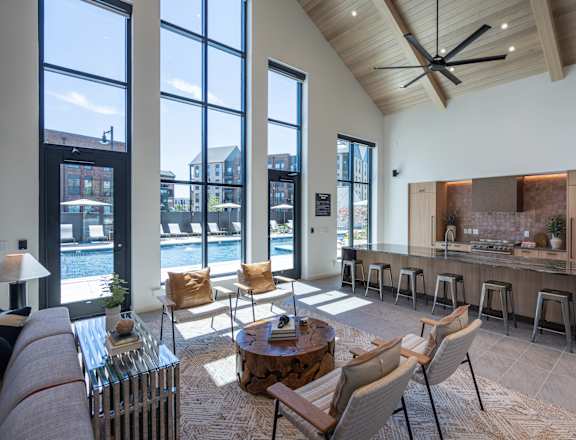 A modern living room with a bar area and a view of the outdoors through large windows.