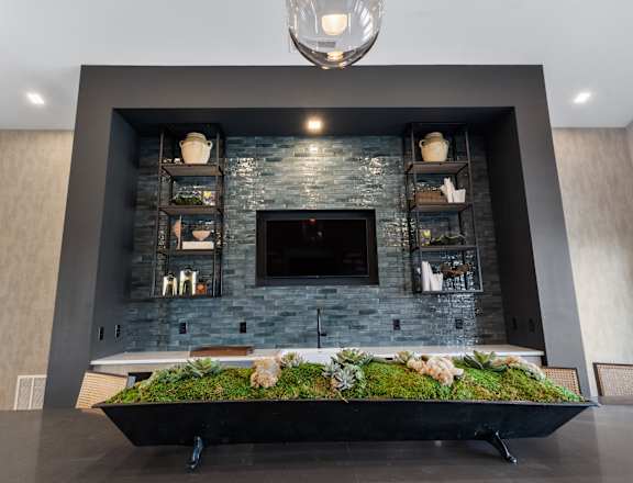 A modern fireplace with a stone surround and a green planted planter in front.