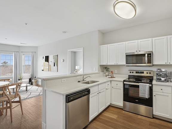 A modern kitchen with white cabinets and stainless steel appliances.