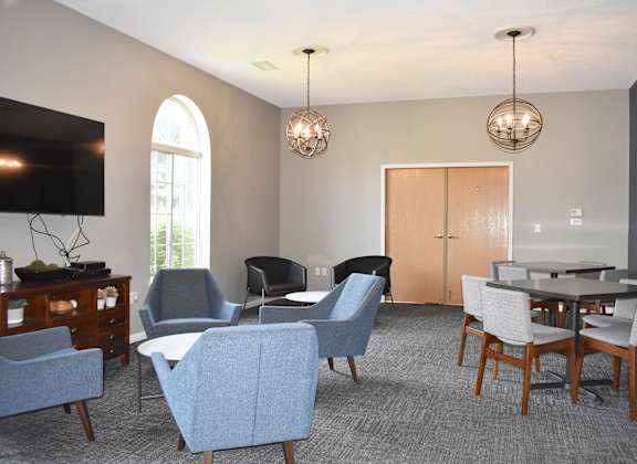 A living room with a grey carpet and a wooden dining table.