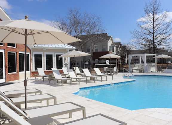 A pool area with a white umbrella and chairs at Carlton Park Apartment Homes, 39232