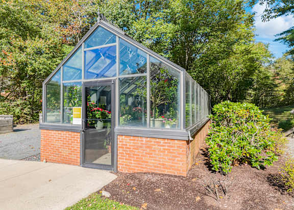 A greenhouse with a brick base and glass panels.