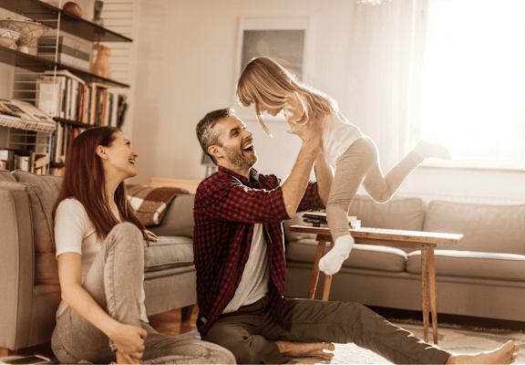 A man and woman are playing with a child in a living room.