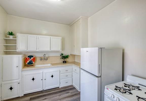 an empty kitchen with white cabinets and appliances and a refrigerator