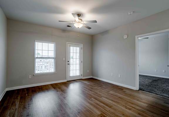 A room with a ceiling fan and wooden floors.