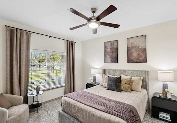 A bedroom with a bed, chair, and window.