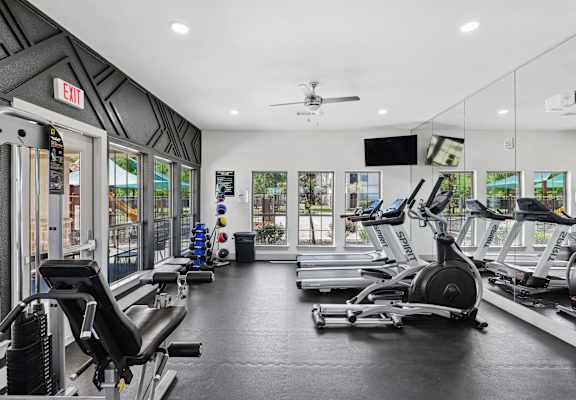 A gym with a row of treadmills and elliptical machines.
