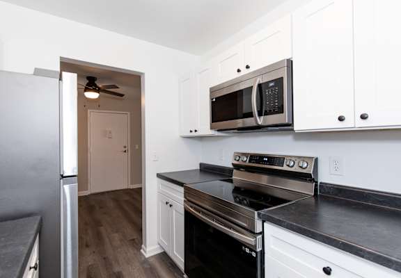 a kitchen with white cabinets and black counter tops and stainless steel appliances