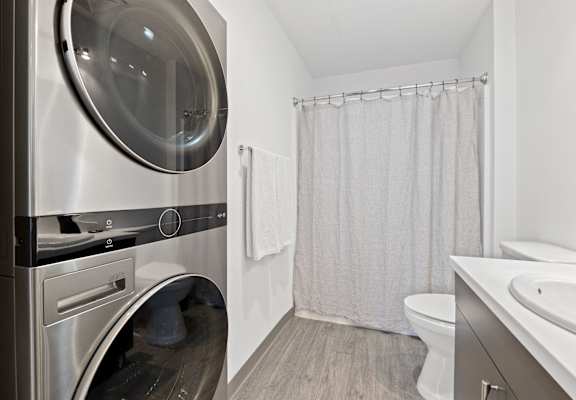 a washer and dryer in a bathroom with a shower and a toilet