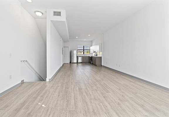 the living room and kitchen in a new home with white walls and wood flooring