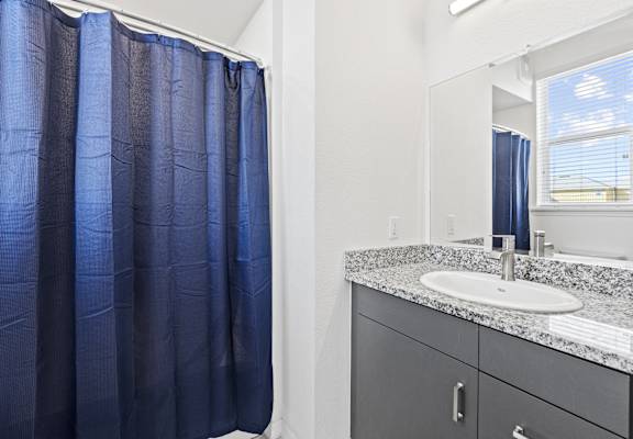 a bathroom with a shower and sink and a blue shower curtain