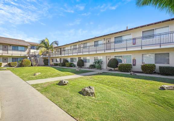 A sunny day at a well-kept apartment complex with a clear blue sky.
