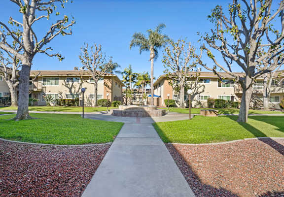 A pathway leads through a landscaped area with trees and shrubs.