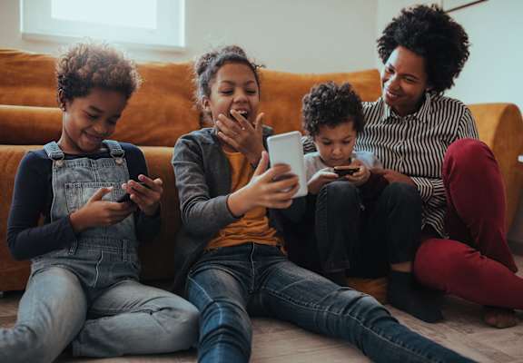 three young people sitting on a couch playing on their cell phones