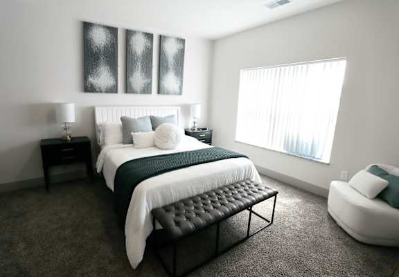 A bedroom with a large bed and a chair.