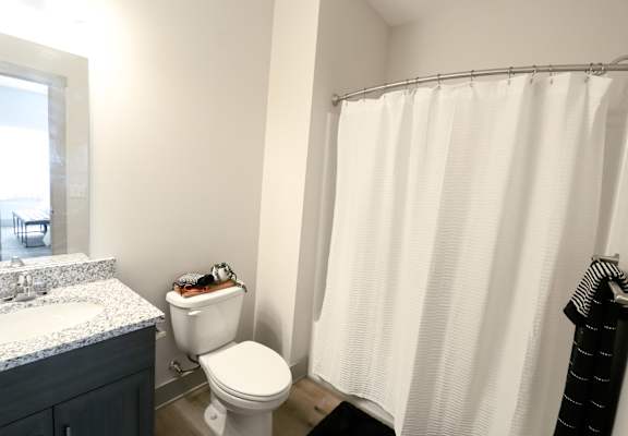 A white shower curtain hangs in a bathroom.