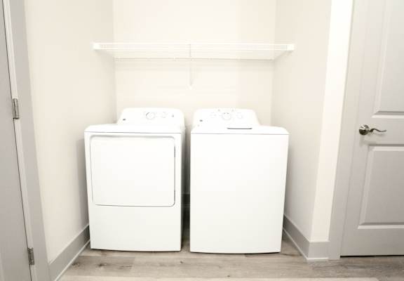 Two white washing machines in a small laundry room.